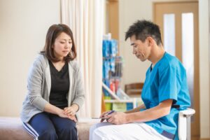 夏の首の痛みと頭痛を相談する女性とフジイ整骨院院長