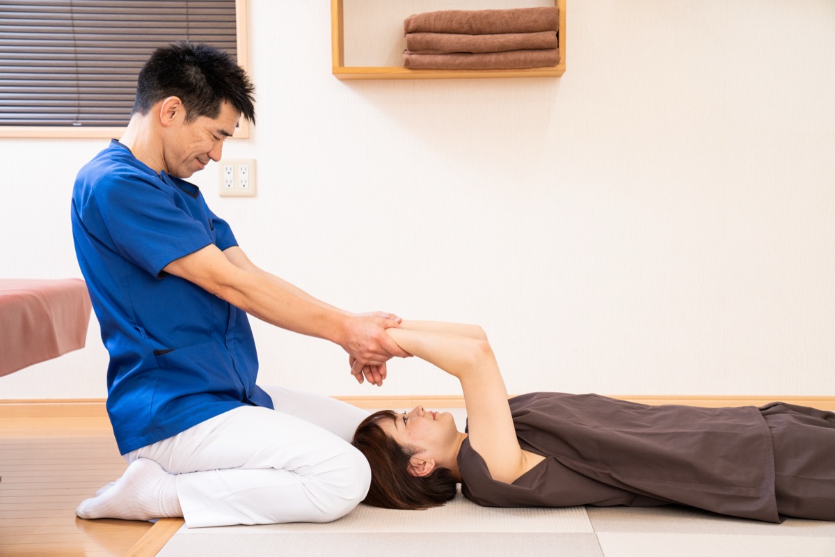 仰向けで腕を持ち上げ、肩甲骨と胸まわりの動きを整える施術