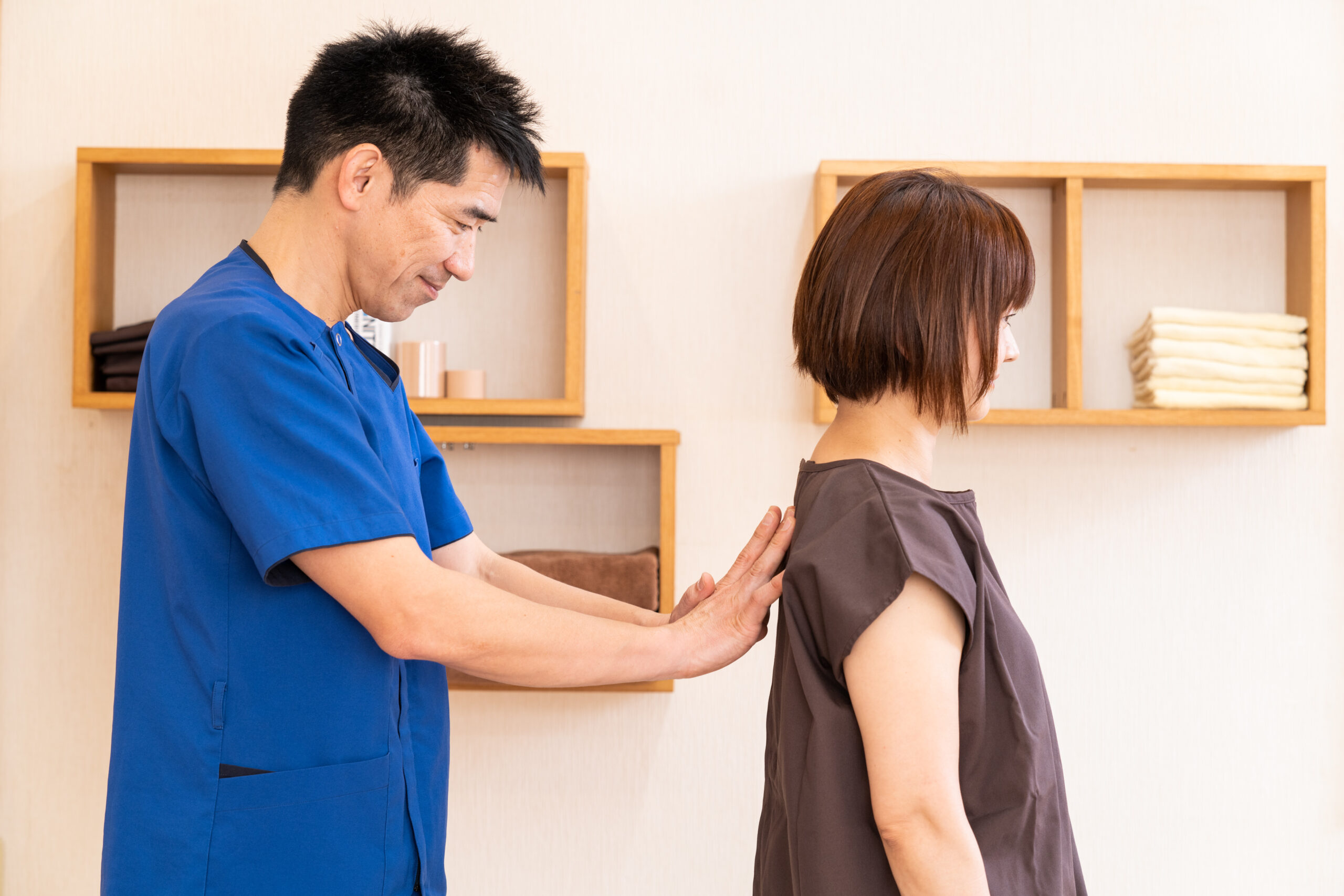 背中に手を当てて姿勢を確認する整骨院の院長